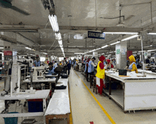 a sewing department sign hangs from the ceiling of a busy factory