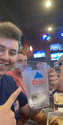 a man holds a coors light glass in his hand