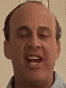 a close up of a bald man making a funny face with his eyes closed .