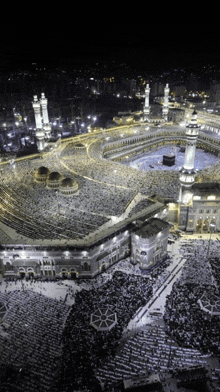 a large mosque is lit up at night with a large crowd of people