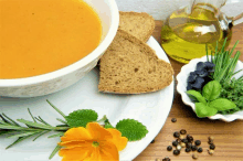 a bowl of soup with bread and a bottle of olive oil