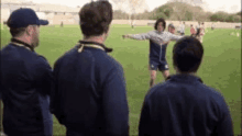 a group of men are standing on top of a soccer field watching a player .