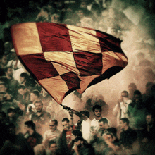 a man holds up a red and gold checkered flag