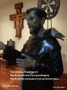 a statue of a man with a bird on his shoulder and a cross behind him