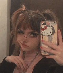 a girl is taking a selfie with a hello kitty phone case on it .