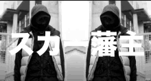 a black and white photo of a man in a hoodie with chinese writing behind him