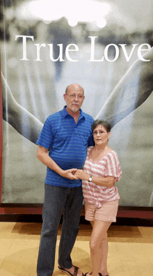 a man and a woman holding hands in front of a true love poster