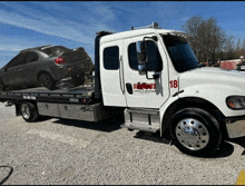 a white tow truck with the number 18 on the side