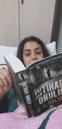 a girl is reading a book titled intihar okulu