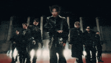 a group of men are standing in a dark room with lights behind them