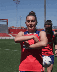 a woman in a red and blue jersey that says ' newcastle ' on the front is holding a soccer ball