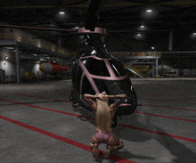 a woman is kneeling in front of a helicopter in a hangar