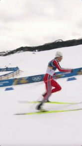 a man is skiing down a snow covered slope with a sign that says olympics in the background