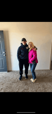 a woman in a pink jacket is standing next to a man in a black hoodie