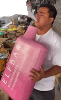 a man is holding a large pink container that says elf bar