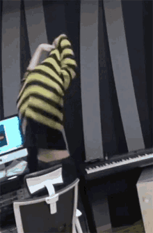 a person wearing a yellow and black striped shirt is standing in front of a keyboard