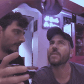a man in a baseball cap is looking at another man in front of a sign that says ' a ' on it