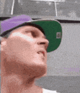 a man wearing a green hat and a purple hat is looking up .