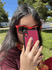 a girl wearing red sunglasses and a red iphone case