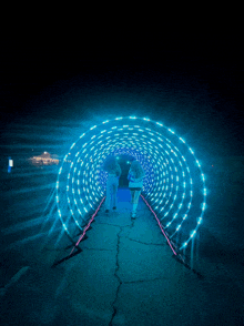 a couple walking through a tunnel of blue lights