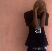 a man covering his face with his hands and a shirt that says why us