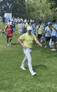 a man in a yellow shirt is walking on a golf course