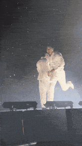 a man in a white suit is holding another man in a white suit