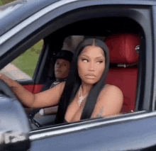 a woman with long black hair is sitting in a car with a man behind her