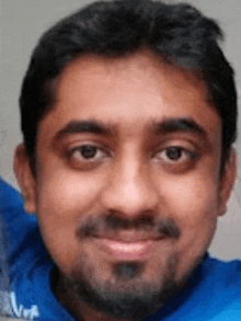 a close up of a man 's face with a beard and a blue shirt .