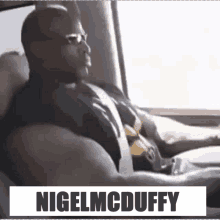 a man is sitting in the back seat of a car with the name nigel mcduffy on the bottom