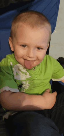 a young boy sticking out his tongue wearing a green shirt with the number 4 on it