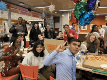 a group of people are posing for a photo in front of a pizza box