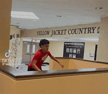 a young boy in a red shirt is jumping over a railing with the word dunkin ' on the wall behind him