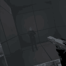 a person holding a gun in a dark room with a man in a helmet behind them