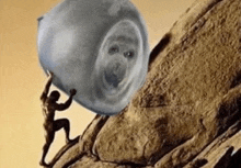 a man is pushing a large rock up a hill with a face on it .