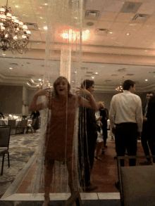 a woman in a brown dress is standing in front of a curtain