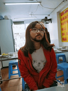 a girl with glasses and a fake beard sits at a table in front of a yellow sign that says " gan "