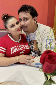 a man and a woman are posing for a picture and the woman is wearing a red hollister shirt