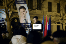 a man stands in front of a banner that says ' én is cigány vagyok ' on it