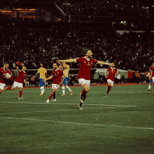 a group of soccer players on a field with one wearing a red jersey that says ' emirates ' on it