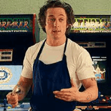 a man wearing an apron is standing in front of an arcade machine called breaker