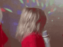 a woman in a red dress is singing into a microphone in a disco room .