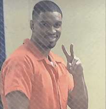 a man in an orange shirt gives a peace sign