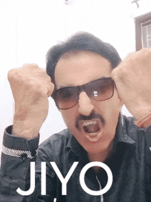 a man wearing sunglasses and a mustache has his fist in the air and the word jiyo is above him