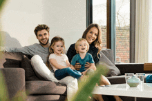 a family is sitting on a couch and smiling