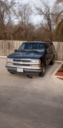 a blue chevrolet suv is parked in a parking lot with a wooden fence in the background