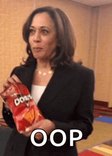 a woman in a suit is holding a bag of doritos chips and says oop