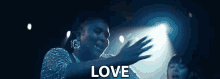 a woman in a silver dress is dancing in a dark room and the word love is visible in the foreground .