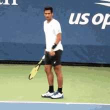 a man is holding a tennis racquet on a tennis court in front of a banner that says us open