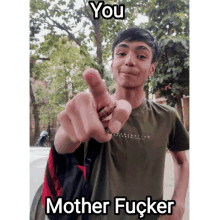 a young man is pointing at the camera with a caption that says " you mother fucker "